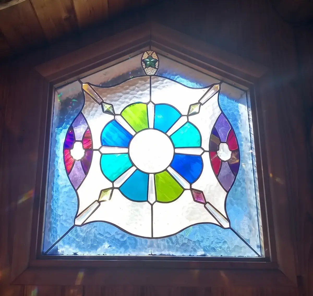 Ventana de vitral circular instalada, con luz entrando por el vidrio de colores